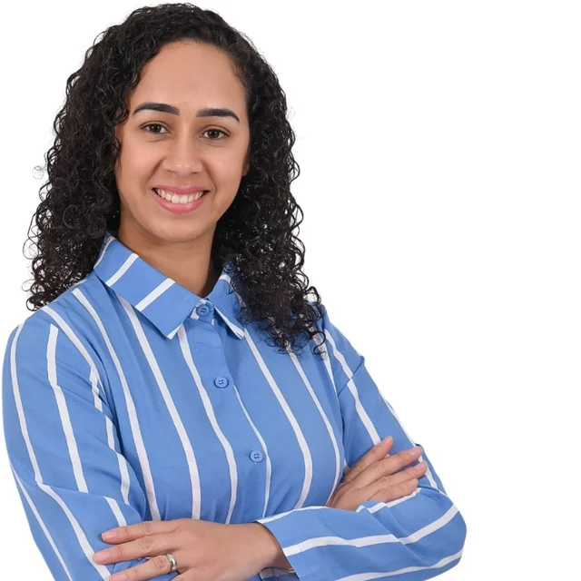 Denise, que faz as Aventuras de Milena, de braços cruzados e sorrindo.